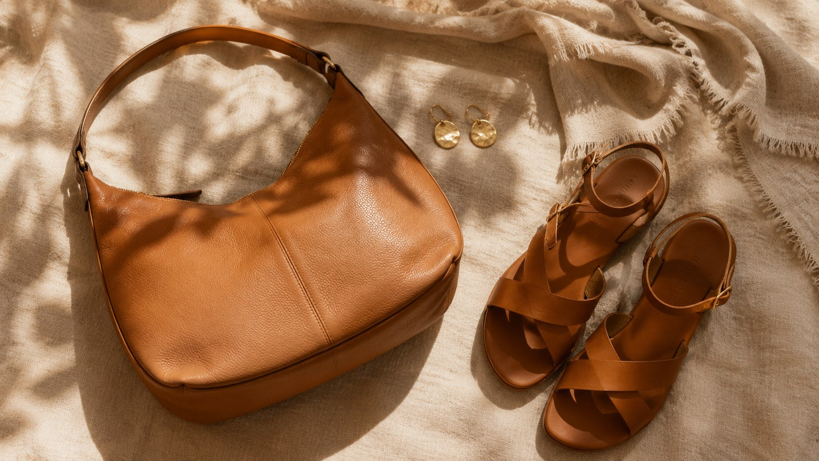 Accesorios de Alma Vittori: bolso de piel camel, pendientes dorados y sandalias